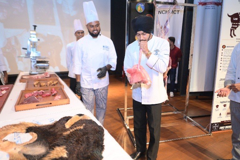 Chef demonstrating a cut to students and faculty